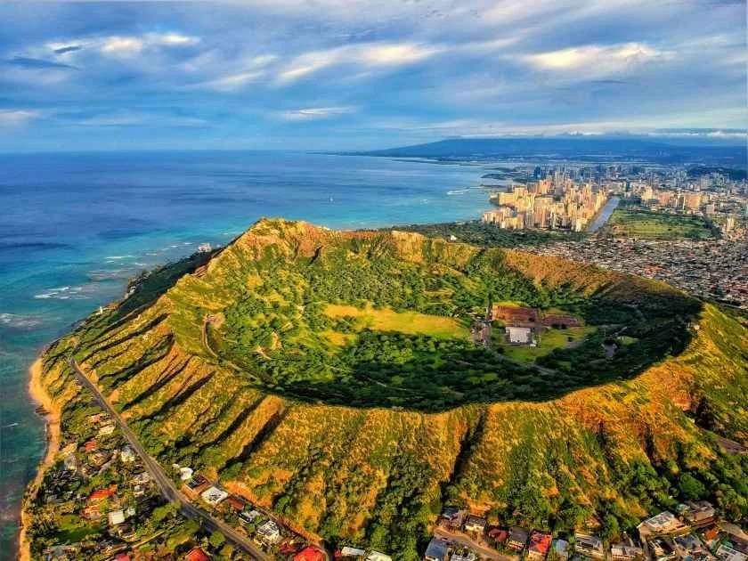 Aerial view of Diamond Head crater with Waikiki and Honolulu stretching along the coast behind it